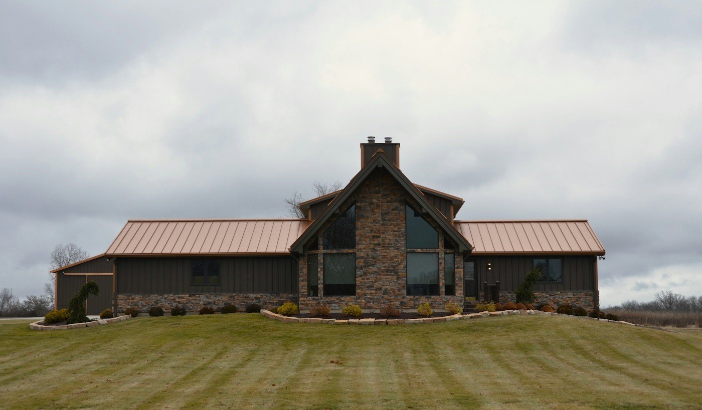 A house with a copper-colored metal roof and a stone front gable