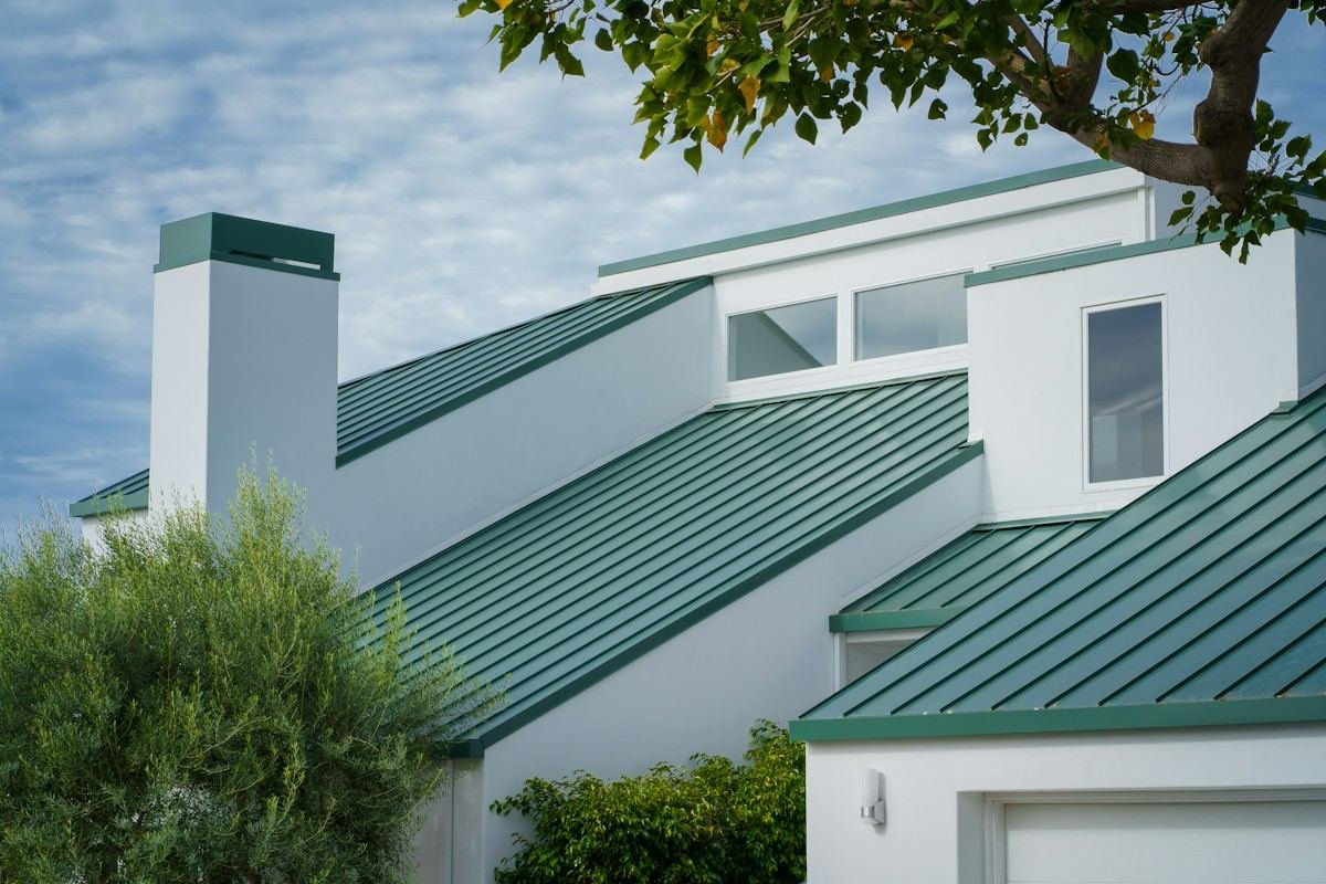 Close view of a green standing-seam metal roof on a white house