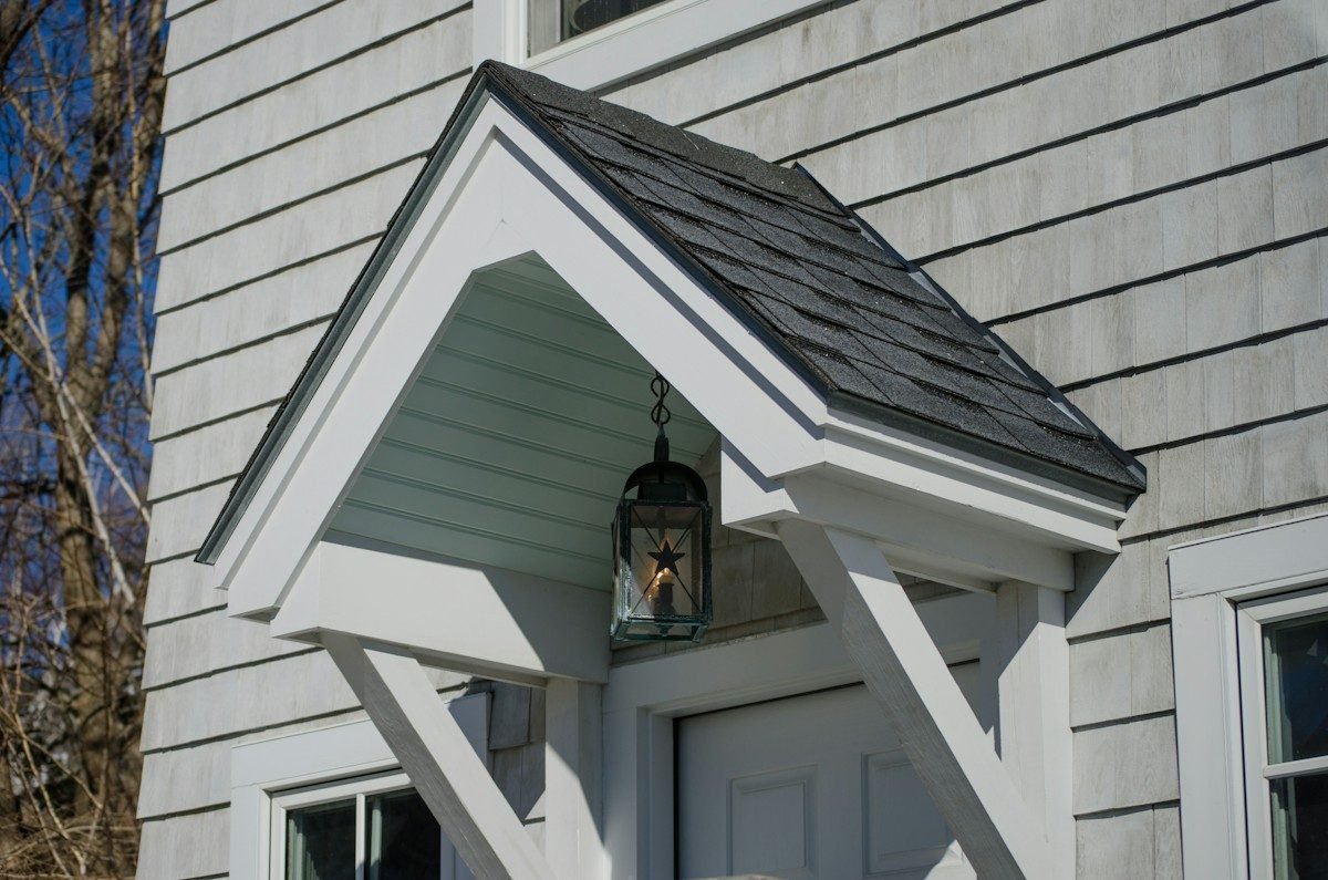 A small shingled gable roof over a side entry