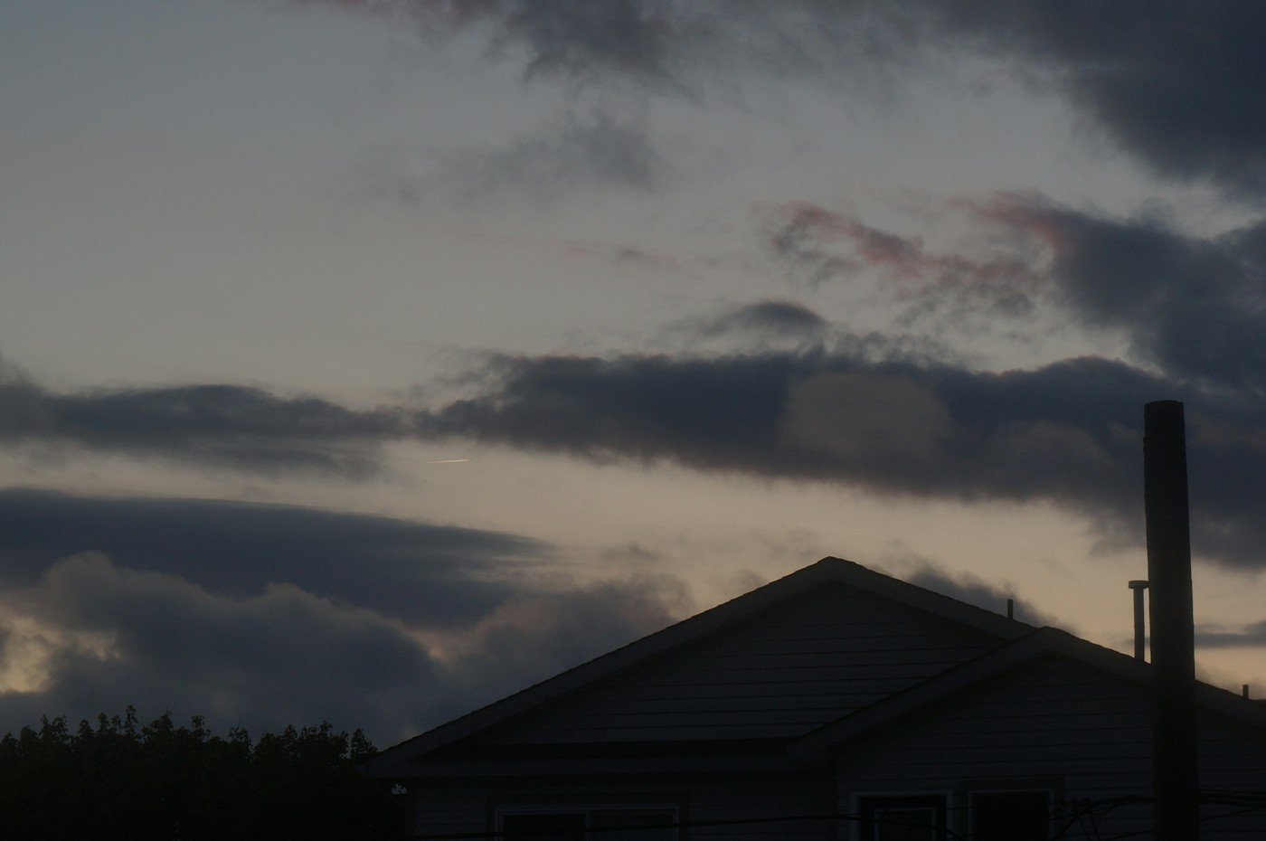 Dark storm clouds over a house roofline at dusk