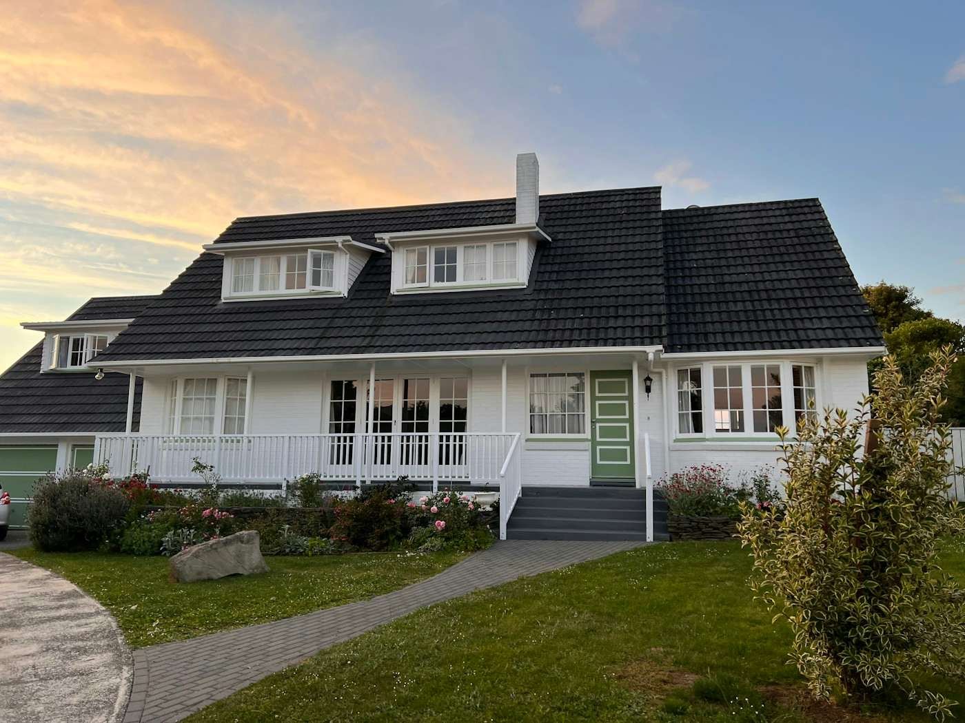 A white house with two dormers and a dark roof at dusk